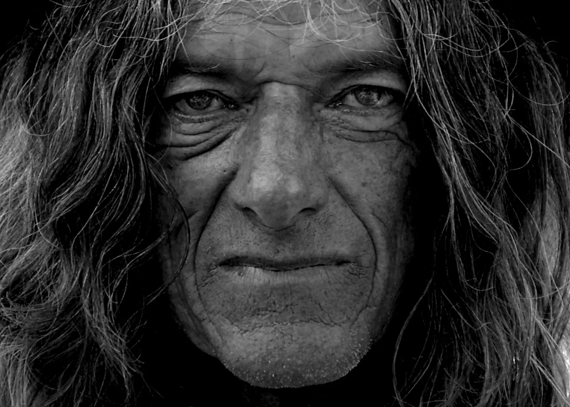 Retrato en blanco y negro de un hombre de pelo largo y rostro curtido