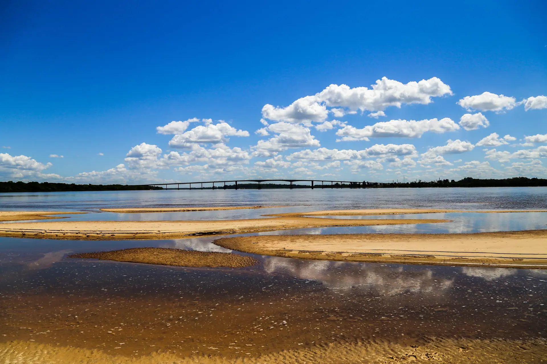 El río Uruguay con un banco de arena y nubes blancas de verano