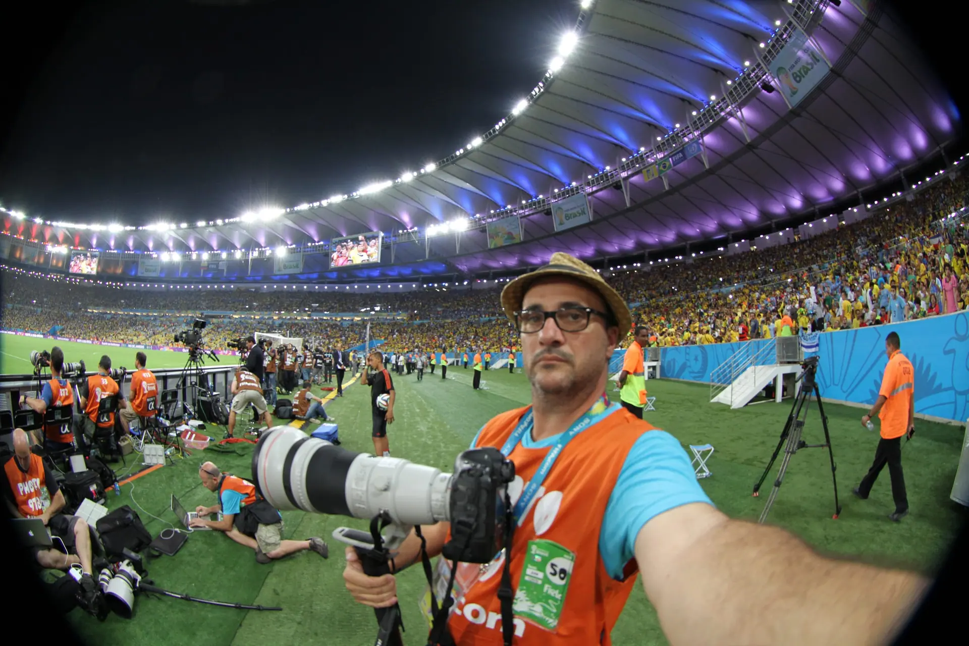 Marcelo Cattani con su teleobjetivo en el campo de juego de un estadio iluminado