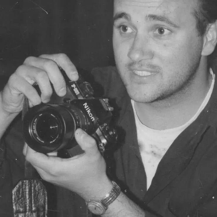 Marcelo Cattani de joven, en blanco y negro, con una cámara Nikon entre las manos